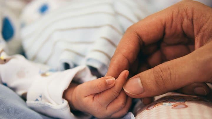 baby holding parents hand