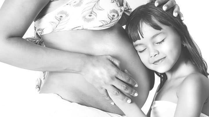 daughter hugging pregnant moms belly