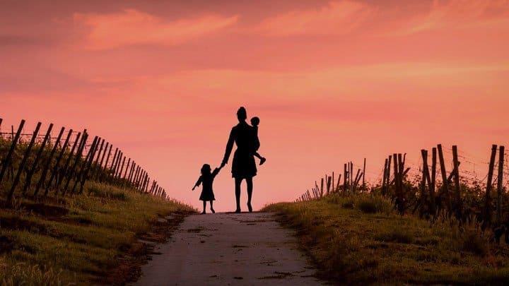 Mother walking with her children towards sunset