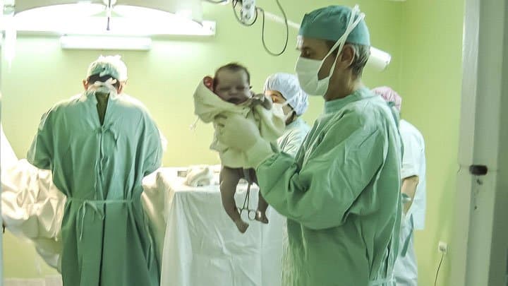 Newborn in delivery room held by doctor