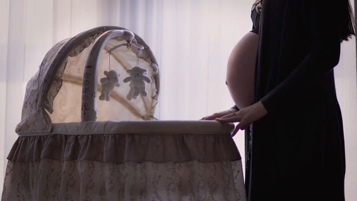 Pregnant mother standing by crib