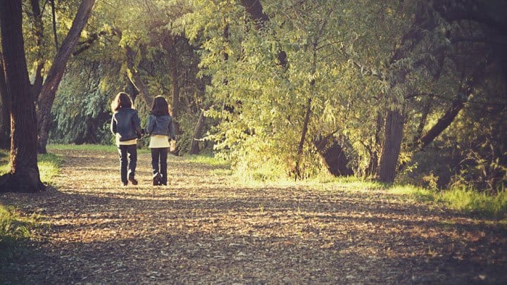 twin girls walking in the woods