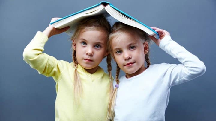 Twin girls holding book
